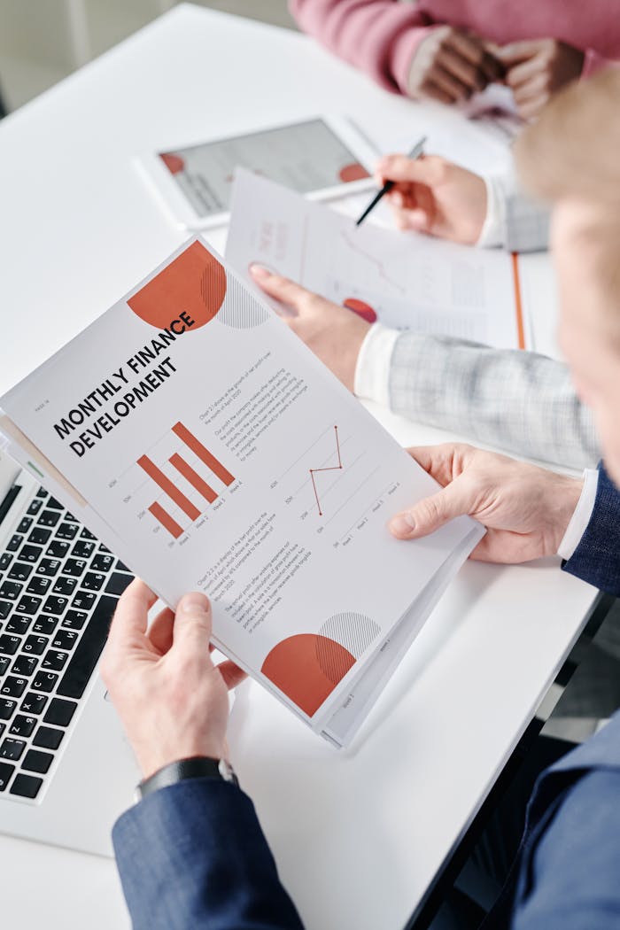 contact-img Professional setting with hands analyzing financial documents during a business meeting.